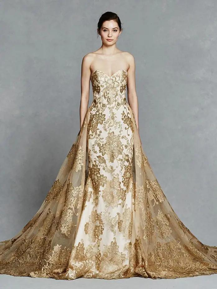This gold embroidered wedding dress features a strapless fit to flare design with illusion back neckline and detachable gold embroidered skirt. Turn heads in this uniquely extravagant wedding dress! Gwendelyn Wedding Dress, Victorian Collection by Kelly Faetanini